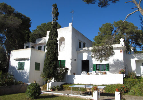White Ibizan-style house facing the sea, surrounded by gardens