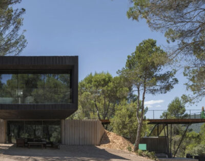 Casa de hormigón con terraza volada sobre bosque y embalse