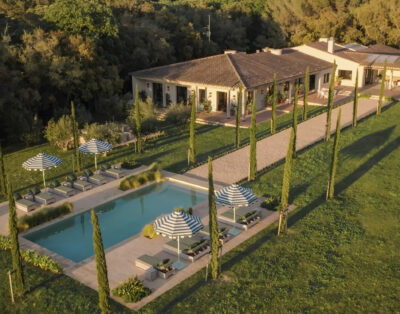 Villa mediterránea con piscina rodeada de cipreses y jardín paisajístico